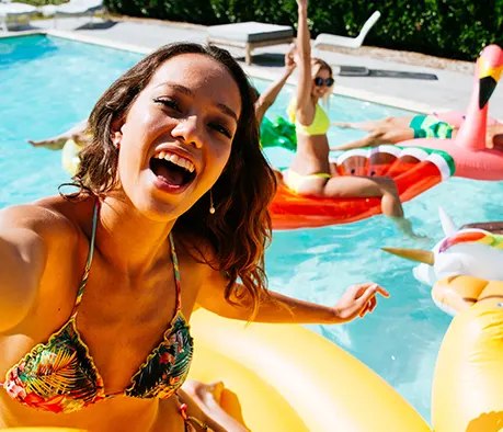 Woman enjoying luxury backyard pool party with colorful floats and outdoor entertainment space