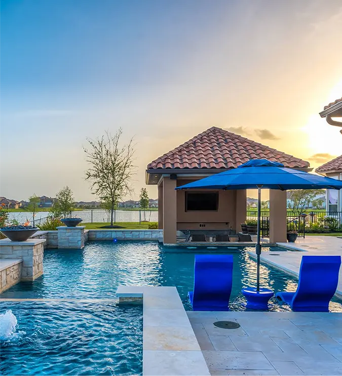 Luxury backyard pool with spa, pavilion, and outdoor entertainment space at sunset