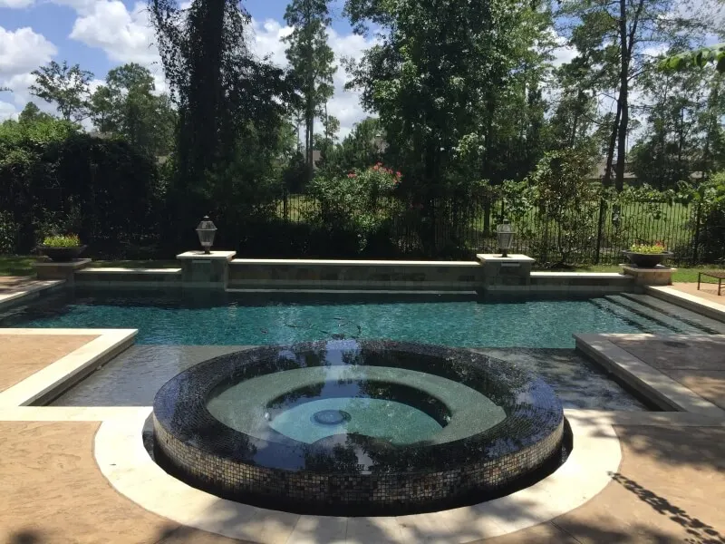 Geometric glass tile spa and luxury backyard pool with lush landscaping and outdoor patio design