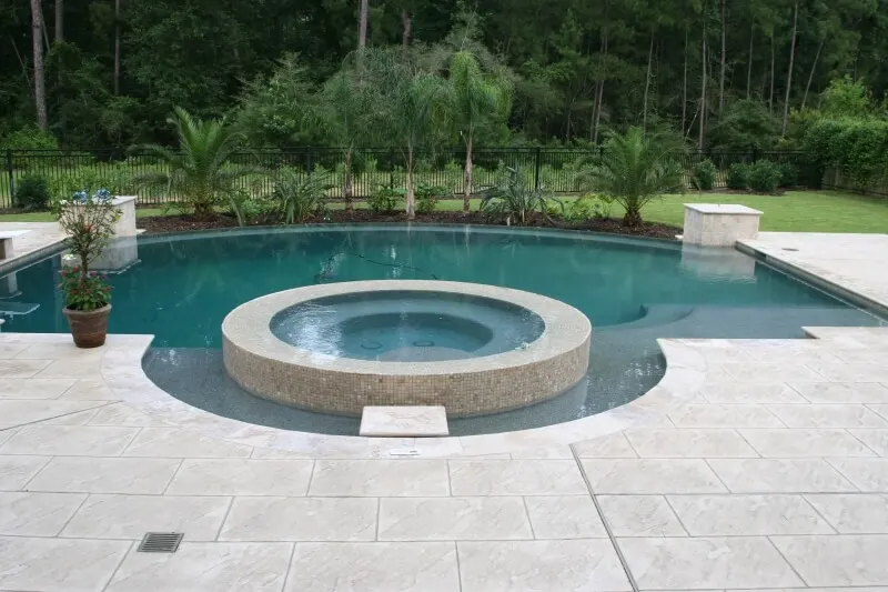 Luxurious backyard swimming pool with circular spa and stone patio design