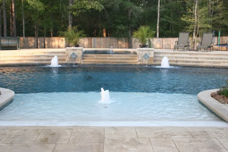 Luxury custom pool with water features and shallow spa in Woodlands backyard entertainment space